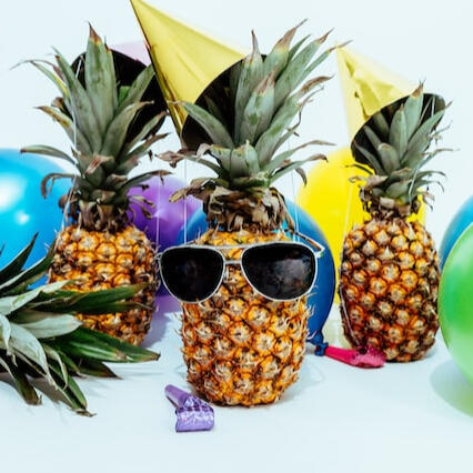 A pineapple wearing sunglasses and a party hat